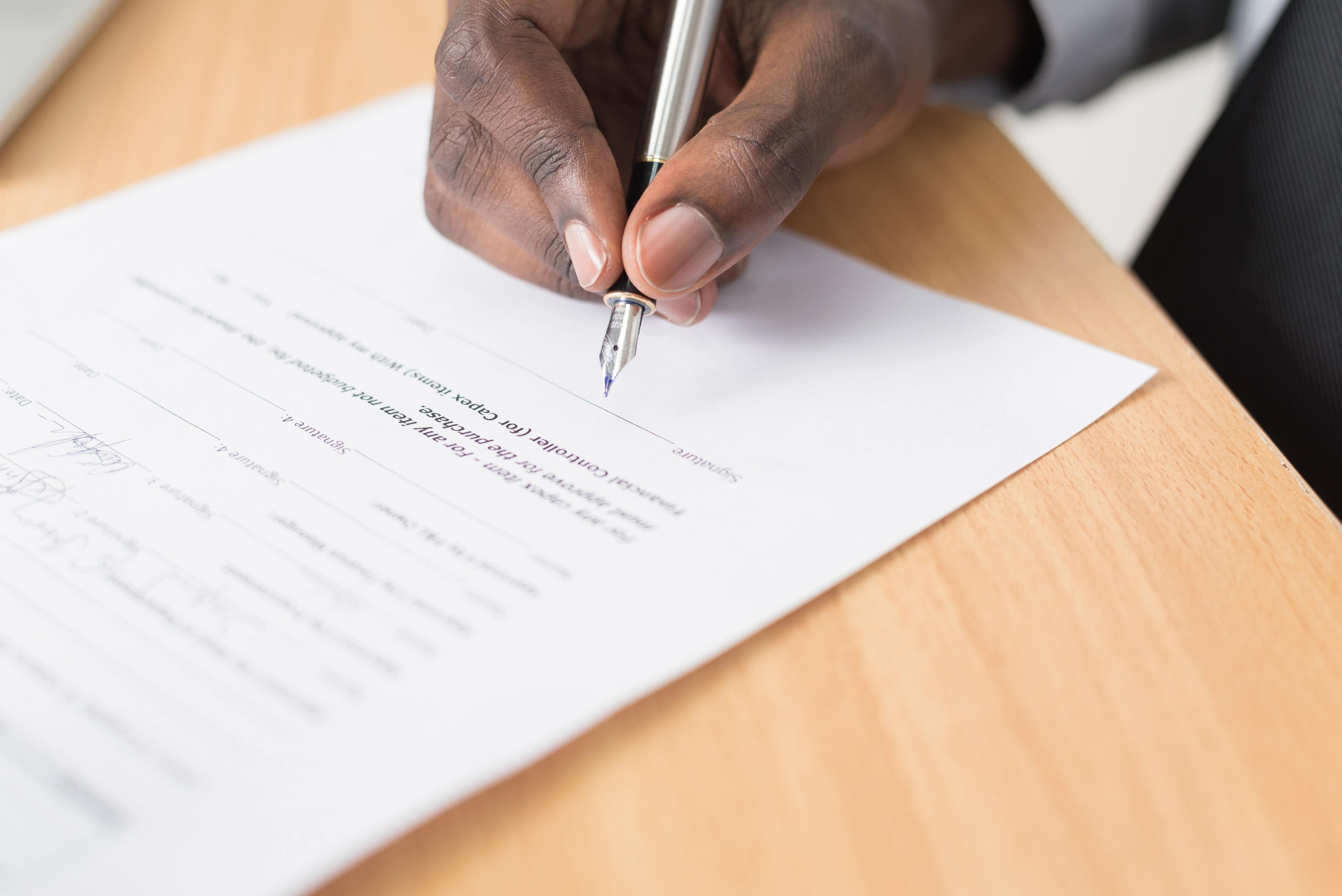 Hand signing a paper on a table