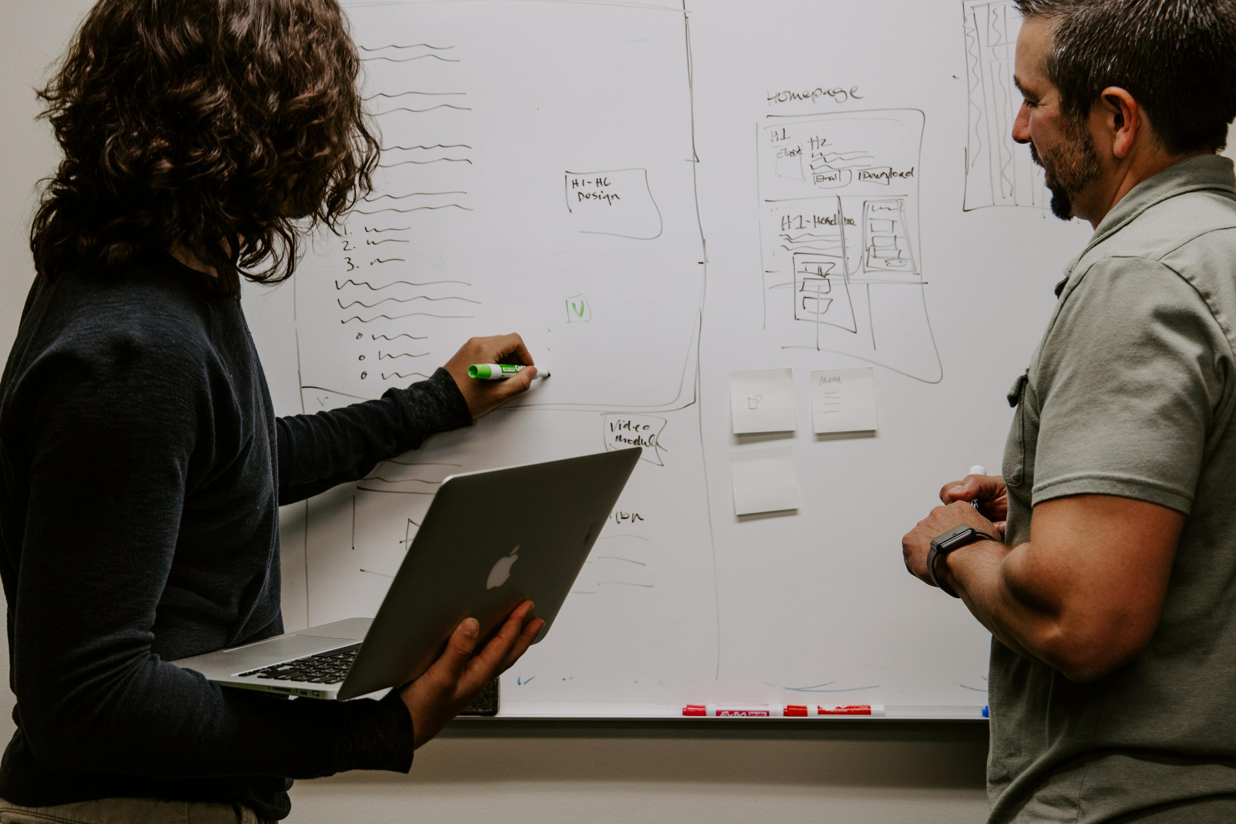 Two person developing application concepts while one of them is drawing on a whiteboard