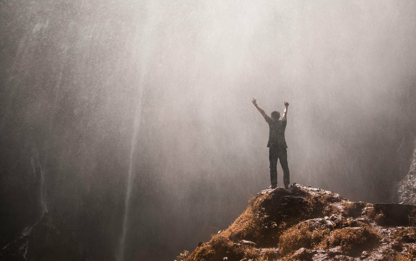 Man on a top of a mountain with his arms up